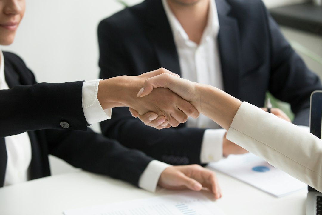 Two people shaking hands over a laptop, symbolising an investment decision
